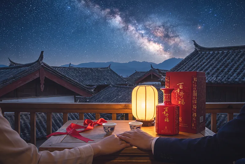 夜晚阳台上，一对恋人的手放在桌上，两只小酒杯和一条红色丝带，头顶是璀璨银河与中式屋檐